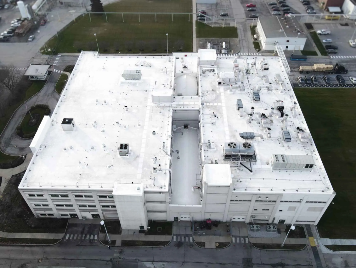 Aerial view of an industrial building's roof restored by Seamless Roofing